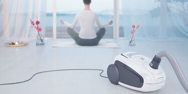 Electrolux Ultra Silencer elektrikli süpürge çalışırken yoga yapan bir kadın