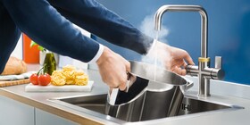 QuickSource musluğundan tavaya sıcak su dolduran bir adam