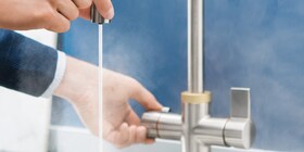 Electrolux QuickSource musluğunun izolasyonlu kısmına dikkatlice dokunan bir adam